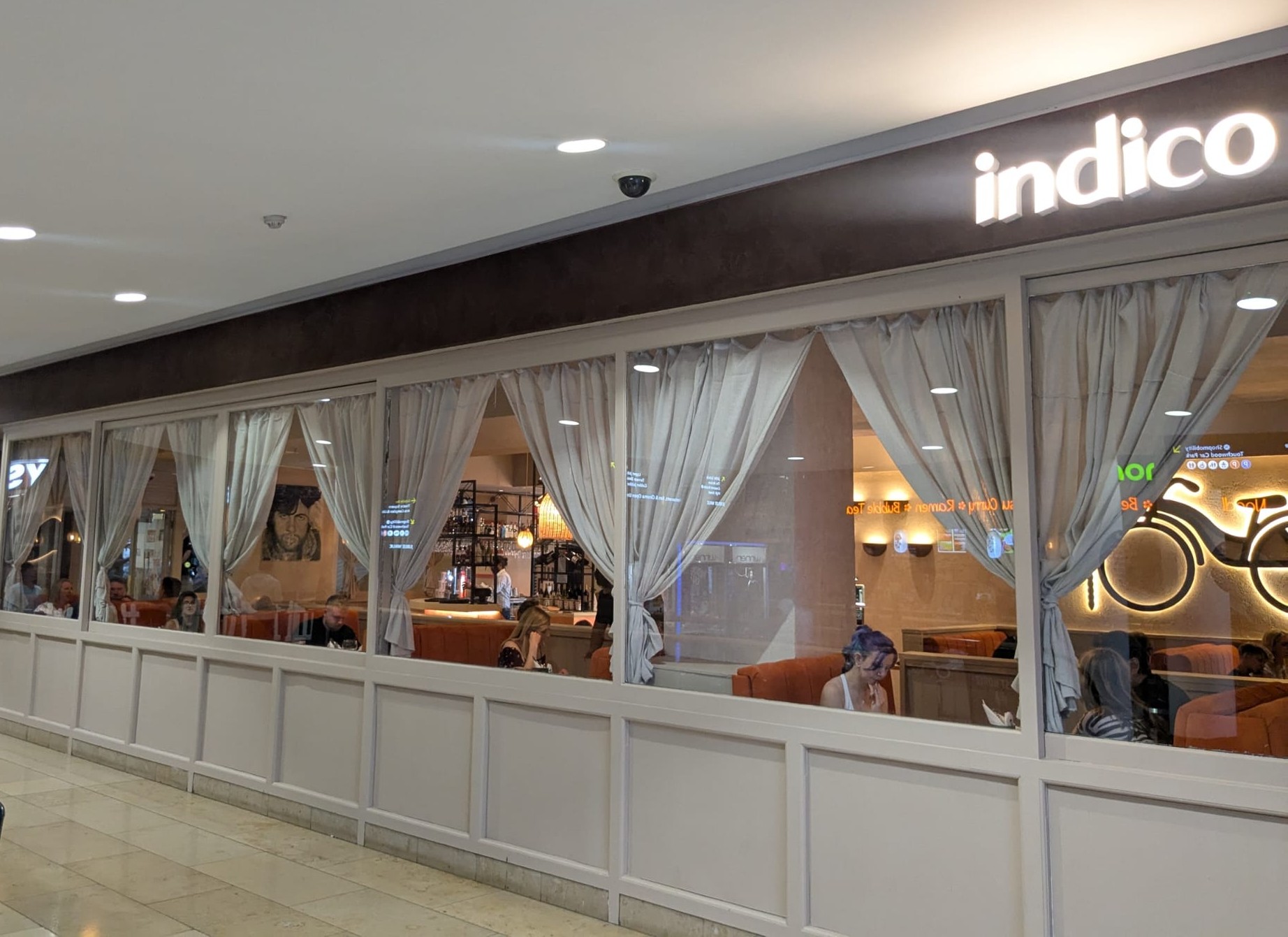 After years of serving up delicious dishes in Shirley, a popular boutique Indian street food restaurant has brought its bold flavours to a new location in Solihull’s Touchwood Shopping Centre.
The move to more spacious premises signals a new chapter for independent brand Indico. Formerly known for its vibrant Bollywood-themed interiors that danced with colour, texture, and cinematic flair, the restaurant has reopened with a new design direction, one of understated elegance and elevated charm.
Situated on the ground floor, the team have reimagined the space with a quiet, elegant decor. Think soft ambient lighting, textured neutrals, artisan finishes, and carefully curated details that whisper sophistication, whilst still paying homage to India with quirky nods to Mumbai street culture.
Indico prides itself on taking diners on a flavourful adventure through the bustling streets of India with a menu bursting with authentic Indian street food. From sizzling chaat and crispy samosas, to smoky tandoori grills and rich, aromatic curries, there’s also a range of comforting classics like butter chicken and dal makhani.
The menu is varied and interesting, options ranging from the popular curries and chaats, to Thali (combining favourite Indian dishes on one plate), Tawa Rolls (Paratha flatbreads cooked on a tawa and finished off with lashings of butter) and even, North-Indian inspired, Paaji Burgers (served in a brioche bun with a side of spicy masala fries.)
Our chosen dishes were evidence of Indico’s popularity among locals. Gol Gappa Bombs (pastry shells filled with seasoned potatoes, chickpeas, sweetened yoghurt, mint and tamarind chutney) gave an explosion of flavour on the tongue. As did the Lollipop Fried Chicken (chicken marinated in a tangy, chilli soy sauce deep fried on the bone for maximum flavour). 
My Butter Chicken (Delhi-style chicken tikka cooked in a rich creamy sauce made of butter and tomatoes finished with fenugreek leaves) and my dining companion’s Chicken Biryani – did you know biryani hails from Persian culture and was later brought to India by the Mughals – were tasty, piping hot and plentiful. (You might wish to skip lunch to make the most of the culinary experience on offer!)
Vegetarians and vegans are well catered for too, with a wide range of wholesome plant-based options crafted with traditional Indian flair like pau bhaji and bhel puri.
A small selection of Indian sweets and desserts, includes Gulab Jamun (soft milk dumplings, deep fried and soaked in a rose-scented sugar syrup and served with panacotta ice-cream) and Gajar Ka Halwa (grated carrots cooked and sweetened in condensed milk and served with panacotta ice-cream) among the highlights. But if these particularly sweet dishes appeal be sure to pace yourself. What remained of my appetite only allowed for the light Mago Passion dessert – (mango and passionfruit sorbet served with fresh strawberries.)
Cocktails are a star attraction, the thoughtfully curated menu celebrating the lively culture of North India – its movies, traditions and ingredients. The drinks are crafted with rich spices and a modern twist, with offerings such as From Goa With Love made with Goan single malt whiskey and Full Moon made with Elderflower Gin. As the designated driver, no sacrifices were made thanks to a decent selection of non-alcoholic signature cocktails. My Malabar Sunset (Afsana Beauty, Mango, Papaya, Pineapple, Passion Fruit and Vanilla) was a refreshing accompaniment to the delicious meal. 
The ’street food’ description, in my opinion, undersells this menu which, based on my first visit, elevates the standard Indian dining experience to a new level of appreciation and exploration. 
Whether you’re craving a quick refuel from the retail therapy, a fun family dinner, or a night out with friends, Indico promises food with soul, service with a smile, and a relaxed and welcoming vibe.
Visit: www.indicostreetkitchen.com
